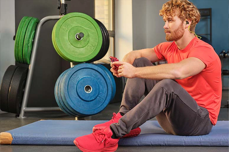 Person mit Bluetooth Kopfhörer im Fitnessstudio.