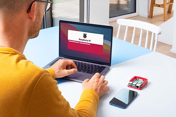 Person sitzt mit einem Laptop und einem Raspberry Pi am Tisch, um Homebridge zu installieren