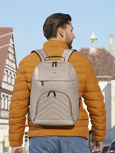 Ein junger Mann ist in der Stadt unterwegs und hat den Hama Laptop-Rucksack "Premium Lightweight" auf dem Rücken