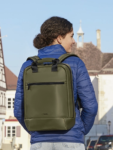 Eine junge Frau läuft durch die Stadt und hat den Hama Laptop-Rucksack "Ultra Lightweight" auf ihrem Rücken