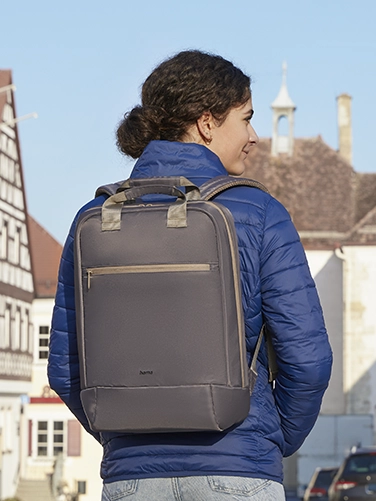 Eine junge Frau läuft durch die Stadt und hat den Hama Laptop-Rucksack "Ultra Lightweight" auf ihrem Rücken